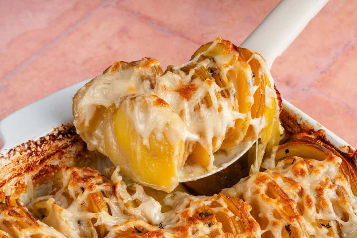 scooping Vegan Dauphinoise Potatoes from the baking dish
