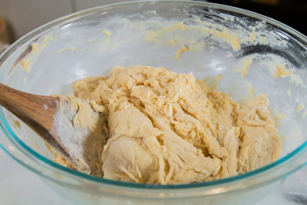 shaggy dough mixed in a glass bowl with a wooden spoon sticking out